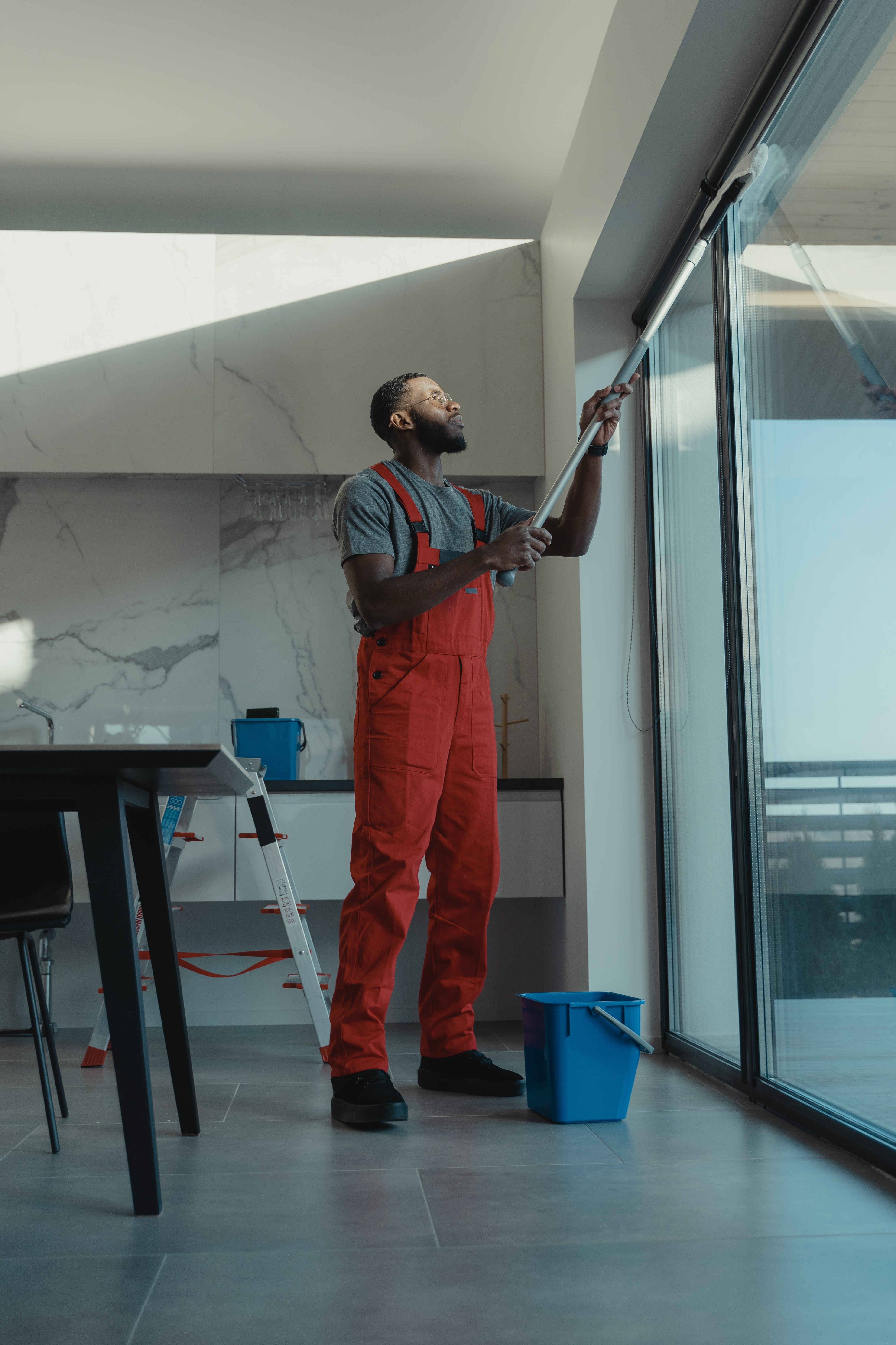 Man cleaning a large sliding glass door with a squeegee.